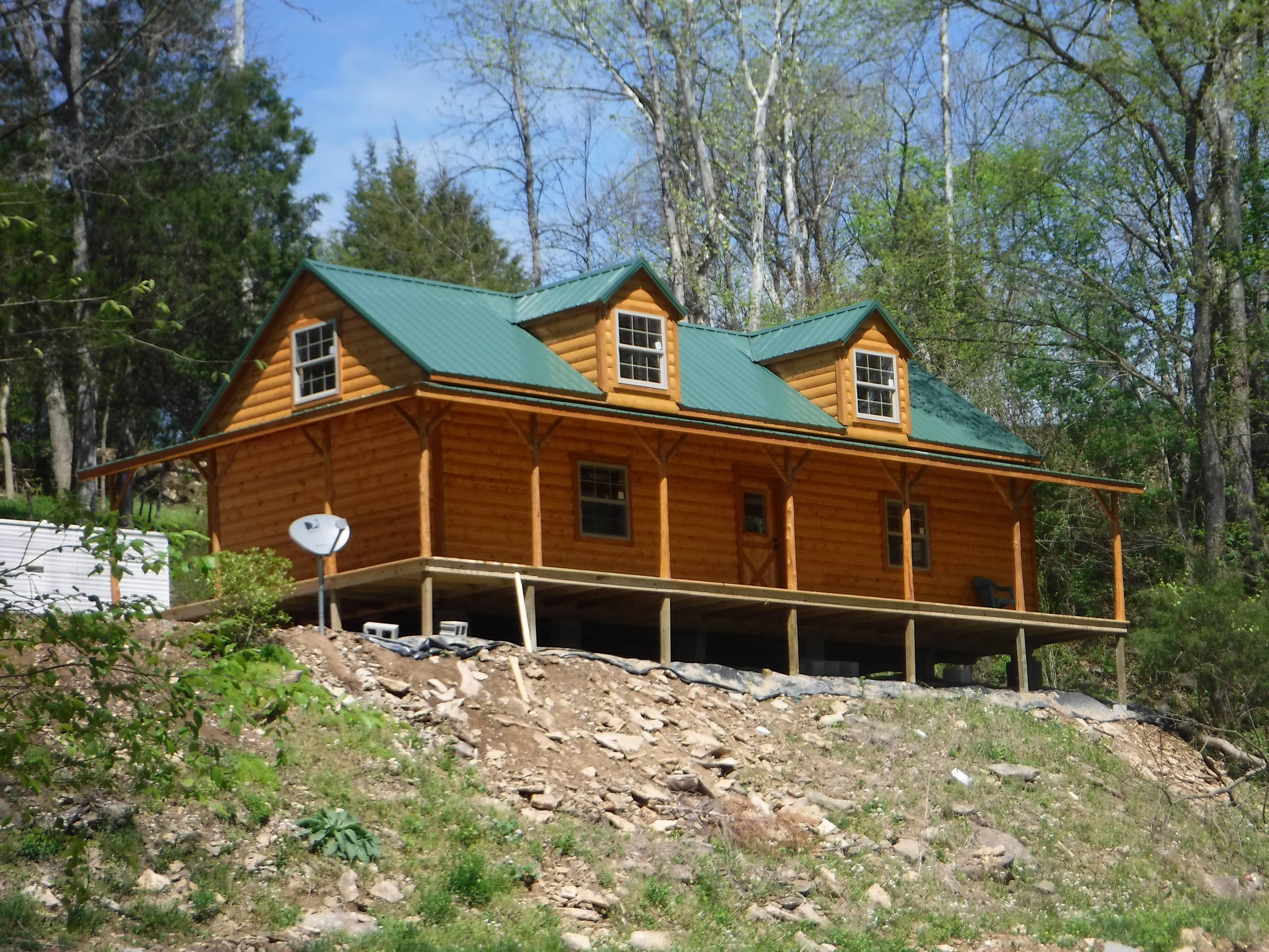 Brown cabin with green roof on a mountain hillside